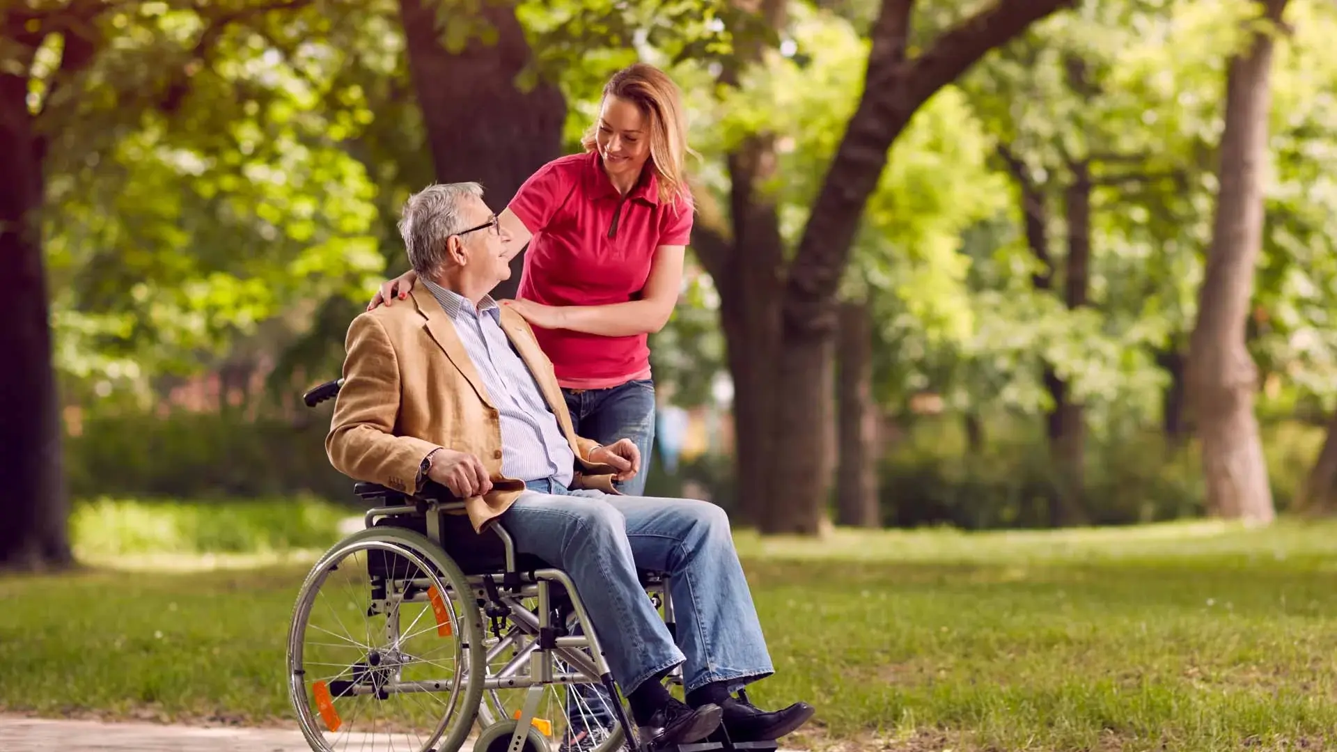 Bild: Ein alter Herr im Rollstuhl und eine junge Pflegerin