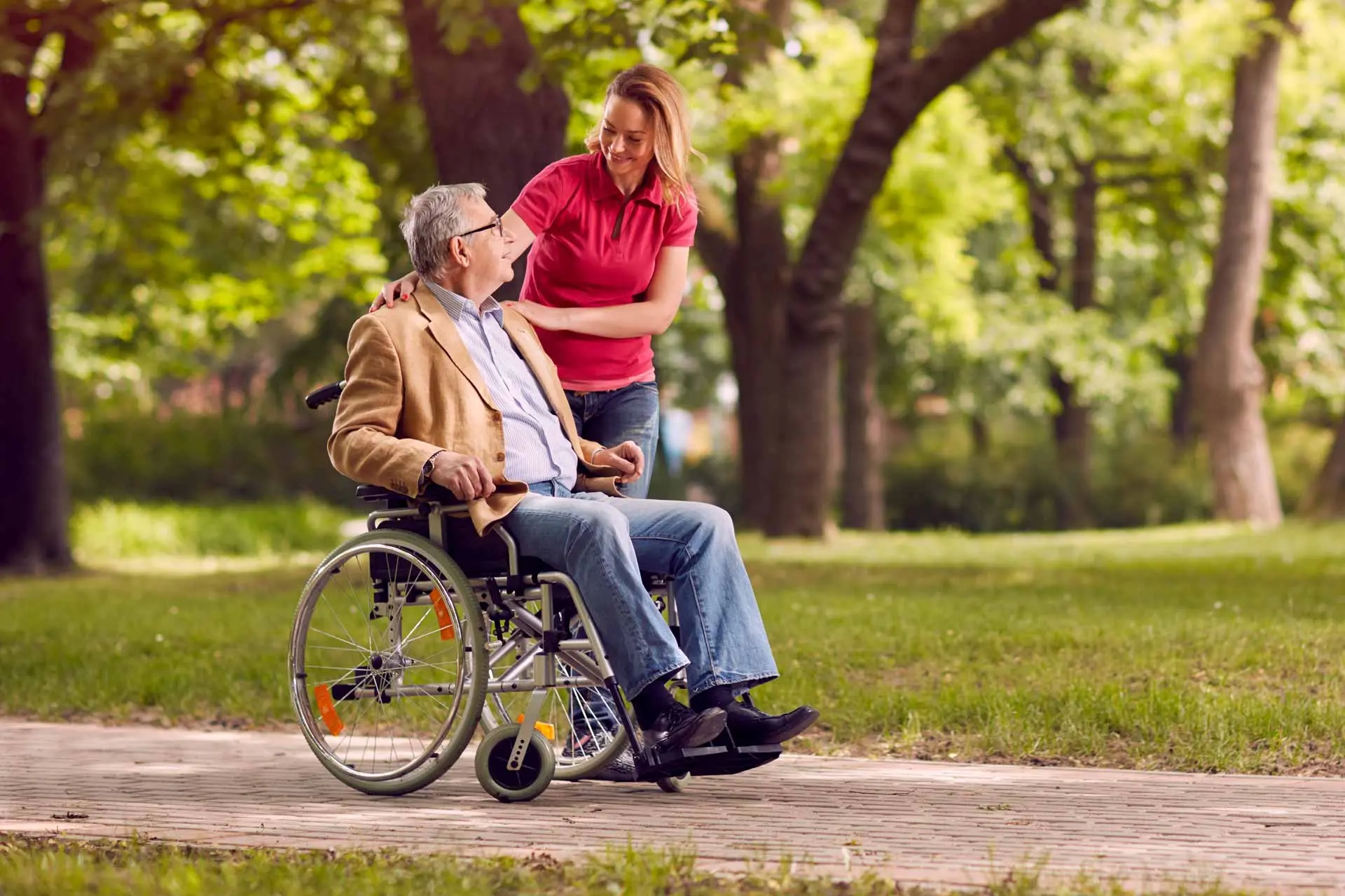 Bild: Ein alter Herr im Rollstuhl und eine junge Pflegerin